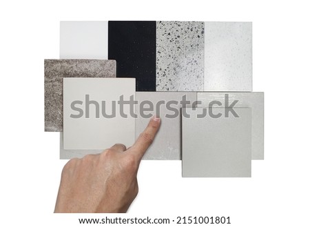 interior architect's hand selecting interior material samples containing tile and artifical stone samples in white, grey ,black color tone isolated on white background  with clipping path.