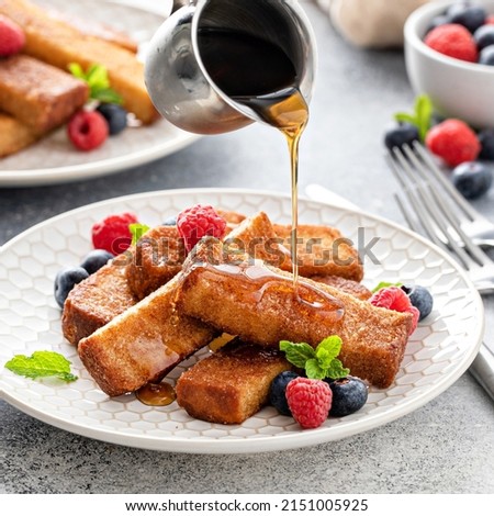 French toast sticks with maple syrup and fresh berries, made in an air fryer, with syrup pouring over Royalty-Free Stock Photo #2151005925