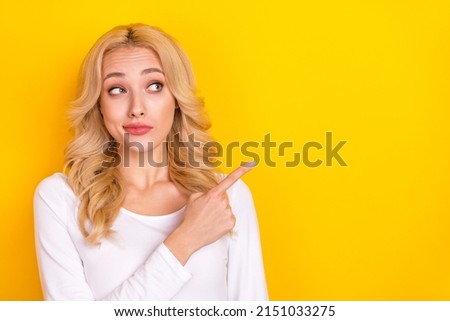 Photo of adorable doubtful lady dressed white shirt looking pointing empty space isolated yellow color background