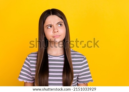Photo of young lovely girl curious look empty space thoughtful isolated over yellow color background