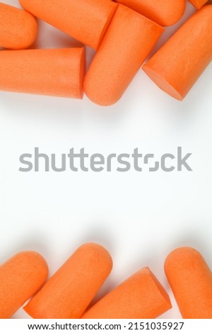 Frame made of orange earplugs on a white background. Close-up.The concept of getting rid of noise in a loud place, hearing protection. Copy space.High quality photo