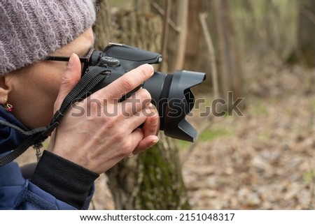 Woman photographer walking and taking picture photo of forest landscape on camera. Shooting nature.