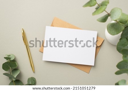 Top view photo of paper sheet craft paper envelope gold pen and white ceramic vase with eucalyptus on pastel grey background with blank space