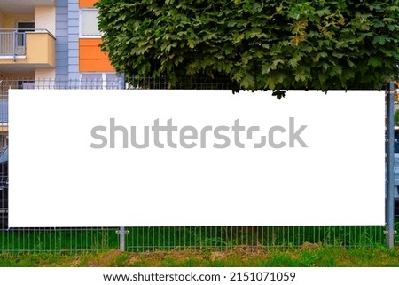 Blank white advertising banner on the fence. Residential ares on a sunny summer evening