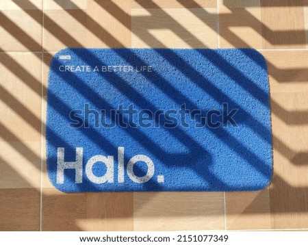 a doormat under the shadow, written Halo meaning Hello in English