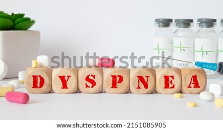 The word DYSPNEA is written on wooden cubes near a stethoscope on a wooden background. Medical concept.
