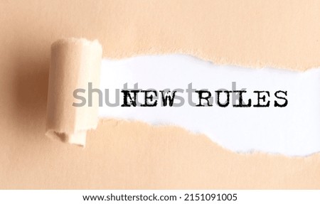 The text NEW RULES appears on a torn paper on white background.