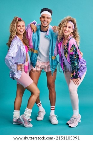 The 80s was one of the most eclectic decades in fashion. Shot of three young people posing together in 80s clothing against a blue background. Royalty-Free Stock Photo #2151105991