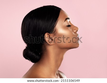 Perfection in profile. Studio shot of a beautiful young woman posing with her eyes closed against a pink background.