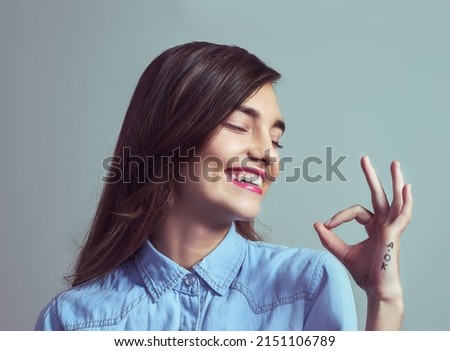Everything is a-okay. Studio shot of an attractive young woman making an a-okay sign with her hand against a grey background.