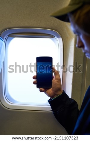 Sharing his view with the world. Shot of a young passenger using his cellphone inside an airplane cabin.