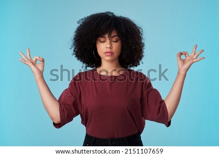 When in doubt, zen it out. Studio shot of an attractive young woman meditating against a blue background.