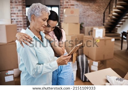 Every home has a history. Shot of a senior woman looking at a photograph with her daughter while packing boxes on moving day.