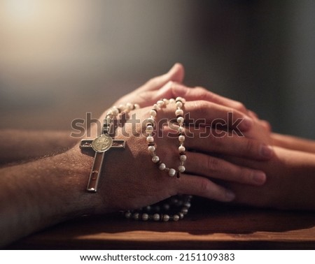 Seeking guidance from a spiritual leader. Cropped shot of two people praying while holding a rosary. Royalty-Free Stock Photo #2151109383