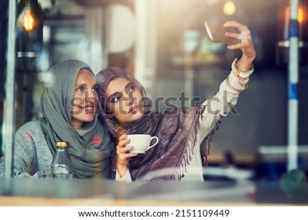 Whats better than coffee A best friend. Shot of two women taking selfies with a mobile phone in a cafe.