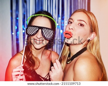 TGIF. Shot of two beautiful young women having fun with props in a photobooth. Royalty-Free Stock Photo #2151109713