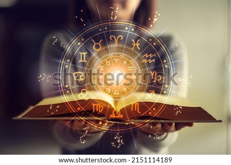 Woman holding a astrology book. Astrological wheel projection, choose a zodiac sign. Astrology esoteric concept. Royalty-Free Stock Photo #2151114189