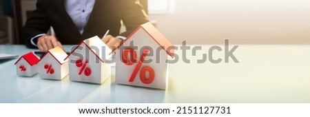 Close-up Of A House Models With Percentage Symbol In Front Of Businessperson Working In Office