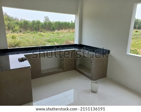 photo of the room is under construction with a rough finish, plastered walls, concrete floor,Modern house with landscaping on front,Entrance porch with concrete floor and square columns. Exterior hous