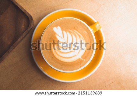 Cup of cappuccino coffee with Rosetta latte art stands on a wooden desk, top view Royalty-Free Stock Photo #2151139689