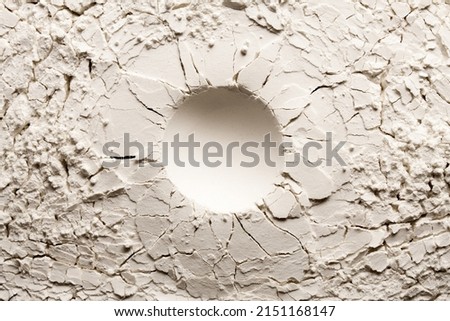 Round crater on white backgroung with crack. Cracked background with a round hole.