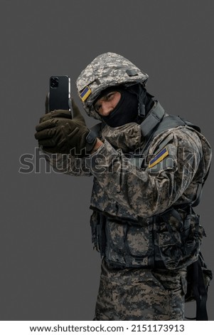 Shot of cheerful military man dressed in modern camouflage uniform taking selfie. Information warfare.