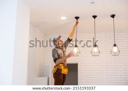 Electrician worker installation electric lamps light inside apartment. Construction decoration concept. Royalty-Free Stock Photo #2151193337