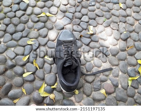 Shoes and black stones on the floor and leaves in the yard