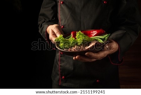 Grilled and sliced beef steak with grilled vegetables served on plate on black background presentation in chef hands. Grande cuisine.