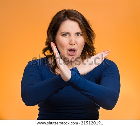Portrait angry middle aged woman with X gesture to stop talking, cut it out, dont go there, isolated orange background. Negative human emotion facial expression feelings, signs symbols, body language