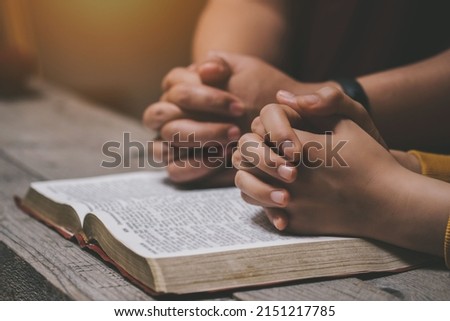 Close-up two christian read bible. Hands folded in prayer on a Holy Bible on wooden table. online group worship, World Day of Prayer, international day of prayer, hope, gratitude, thankful, trust