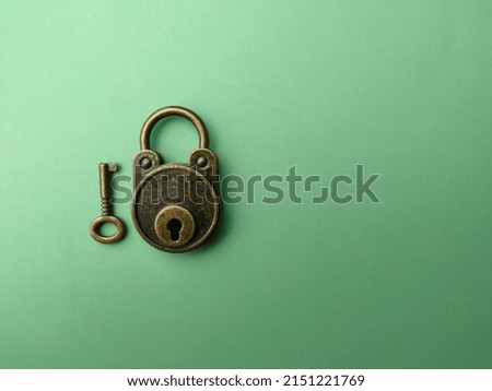 Selective focus.Vintage bronze key and padlock on soft green paper, background image with copy and text space.