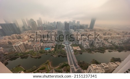 Sunrise over skyscrapers in Barsha Heights district and low rise buildings in Greens district aerial timelapse look down view during all day. Dubai skyline with foggy weather and shadows moving fast
