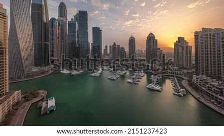 Sunrise over Dubai marina tallest skyscrapers and yachts in harbor aerial morning timelapse before sunrise. View at apartment buildings, hotels and office blocks, modern residential development of UAE