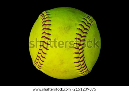 A closeup photo of a used softball isolated on a black background