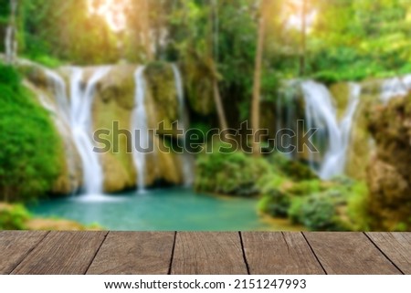 An empty wooden table over a blurry image of the waterfall in the background.