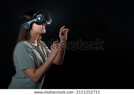 Virtual experience, a young woman using virtual reality glasses, playing a game or interacting with a metaverse, A girl in vr glasses touches a virtual object