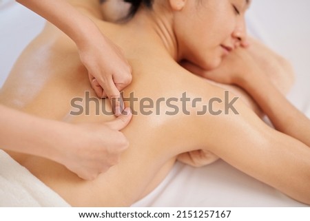 Masseur giving deep tissue back massage to young female client Royalty-Free Stock Photo #2151257167