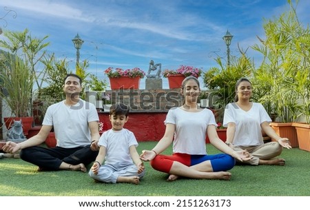 indian family doing yoga in garden  Royalty-Free Stock Photo #2151263173