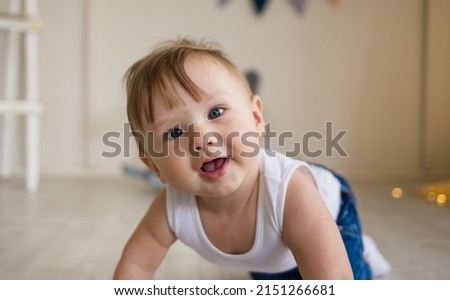 portrait of a baby boy with a squint crawling on the floor in the nursery Royalty-Free Stock Photo #2151266681