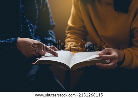 Male reading the Holy Bible by pointing to the character and sharing the gospel with a friend. Holy Bible study reading together in Sunday school.Studying the Word Of God With Friends. Royalty-Free Stock Photo #2151268115