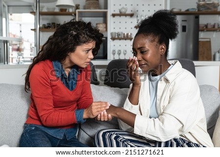 Young African American woman being victim of racism crying to her friend. Teenage female girl crime victim robed on the street. Royalty-Free Stock Photo #2151271621