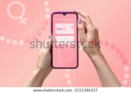 Menstrual cycle tracker mobile app on smartphone screen in hands of woman, graphic representation of period calendar on pink background. Modern technologies for women's health, pregnancy planning Royalty-Free Stock Photo #2151286337