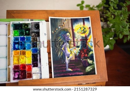 Hand drawn watercolour illustration and palette of aquarelle paints on a wooden easel at home studio. Hedgegoh character 