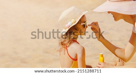 Mom carefully smears her child's face with protective cream on the beach. Skin care. Protection from the sun. Sunscreen for children. Royalty-Free Stock Photo #2151288711