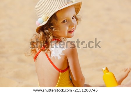 Skin care. Protection from the sun. Sunscreen for children. The Girl is Holding a Moisturizing Sunscreen in her Hands. A child with a sun-shaped suntan lotion on his back on the beach Royalty-Free Stock Photo #2151288745