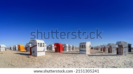panorama wide angle picture of typical beach chairs on the sand at the North Sea coast in Schillig, Germany under deep blue cloudless sky