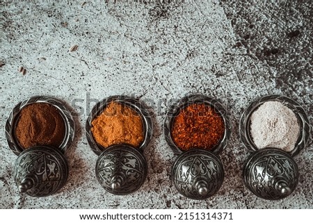 fragrant aromatic,  spices, turmeric, curry, black pepper, paprika and garlic and metal utensils on a gray background