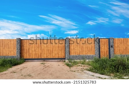 Gabion fence. Gate. Posts full of stones with sections from wooden planks. Countryside style. Exterior garden element design. Security wall. Natural materials. Isolated. Nature texture. Close-up. Royalty-Free Stock Photo #2151325783