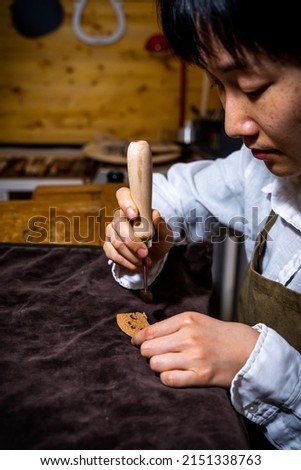 young Chinese woman violin maker signs the jumper of her violin with fire with her name in the workshop
